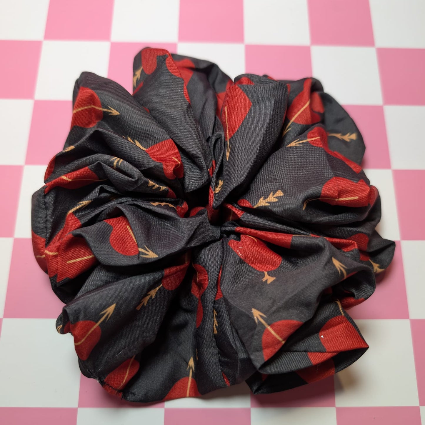 Black scrunchie with red floral pattern on a pink and white checkered background