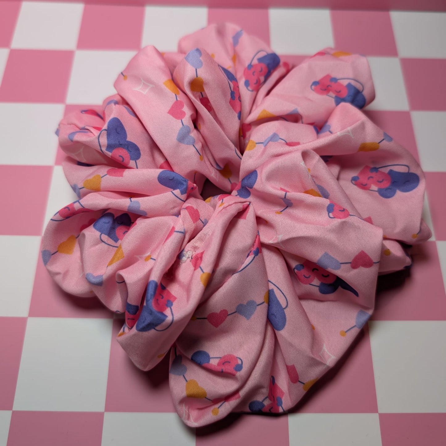 Pink scrunchie with colorful patterns on a pink and white checkered background