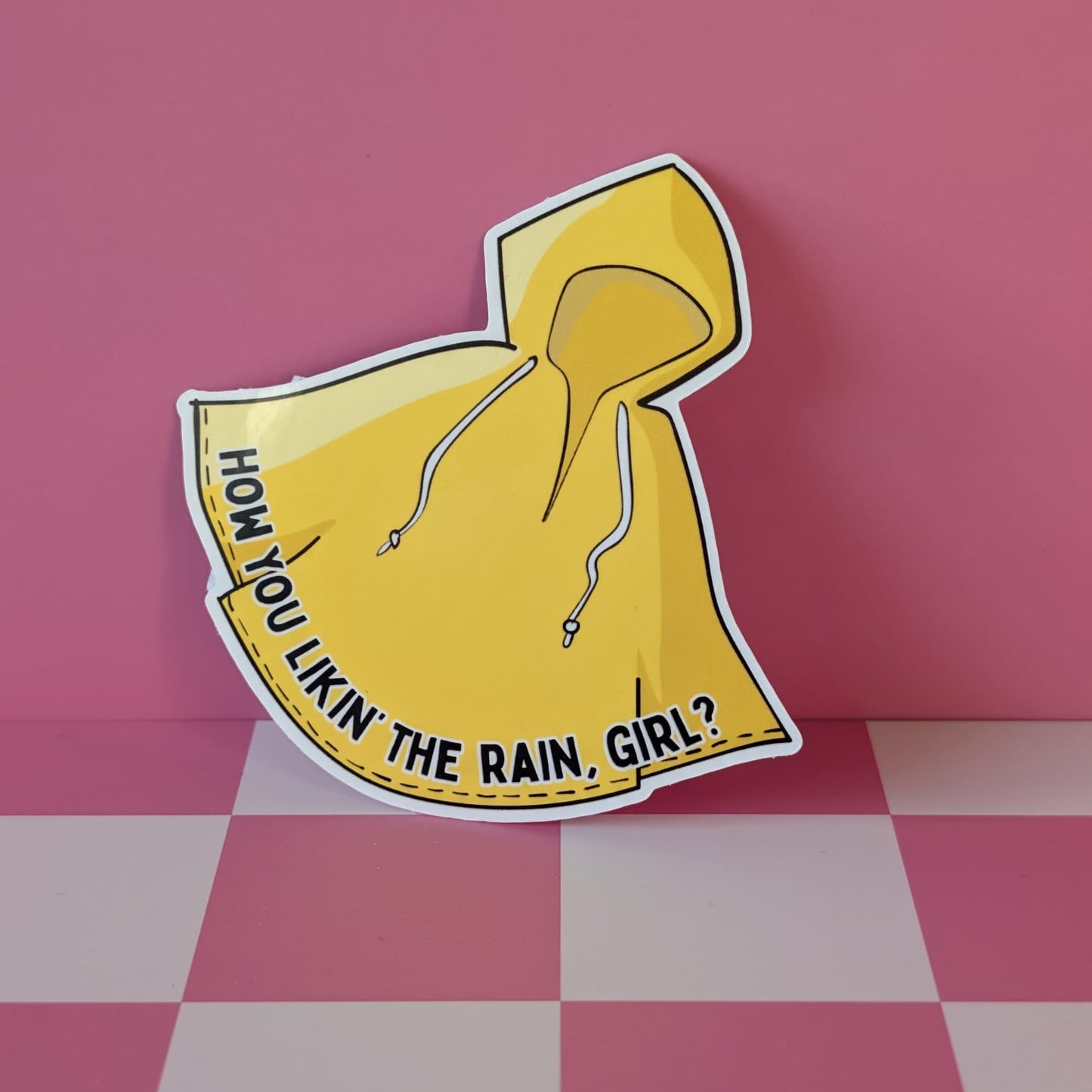 Yellow raincoat-shaped sign with text on a pink checkered floor and background
