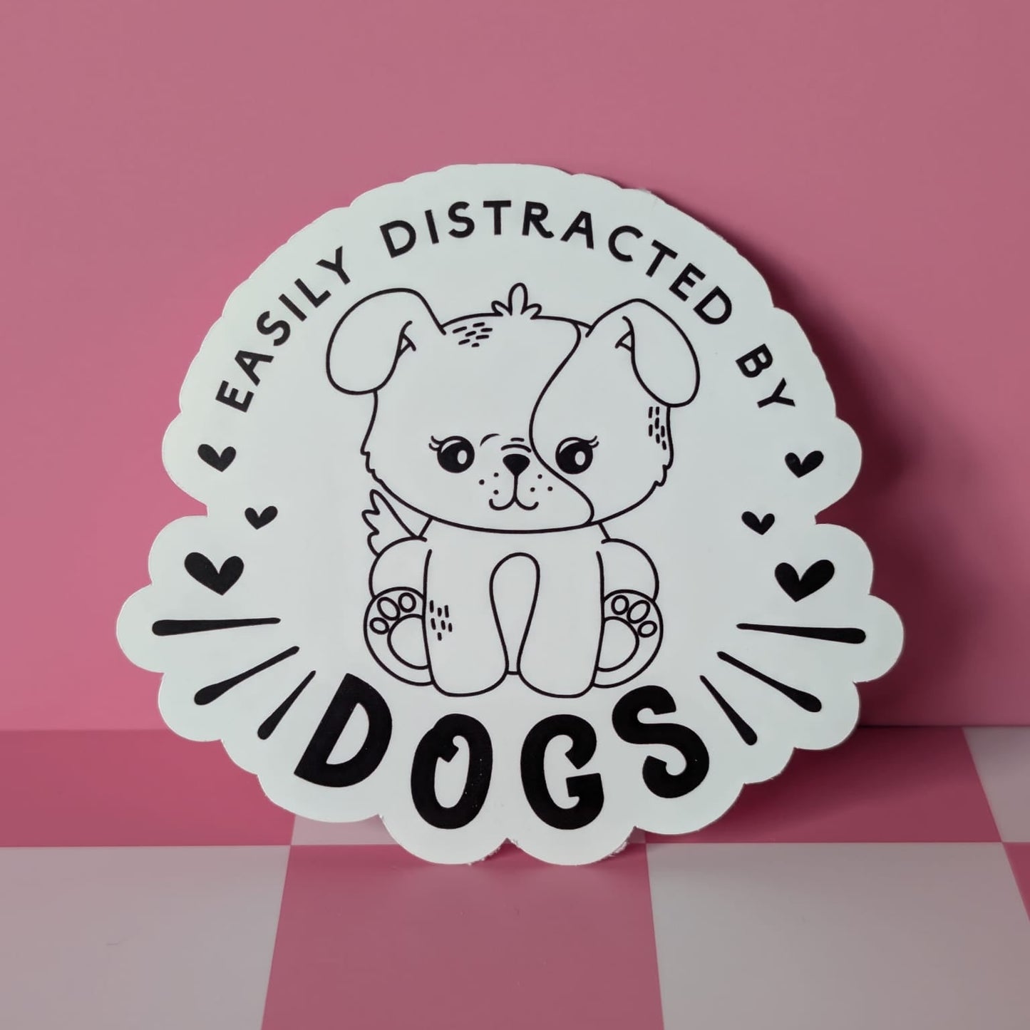 Sticker with a dog illustration and text 'Easily Distracted by Dogs' on a pink background