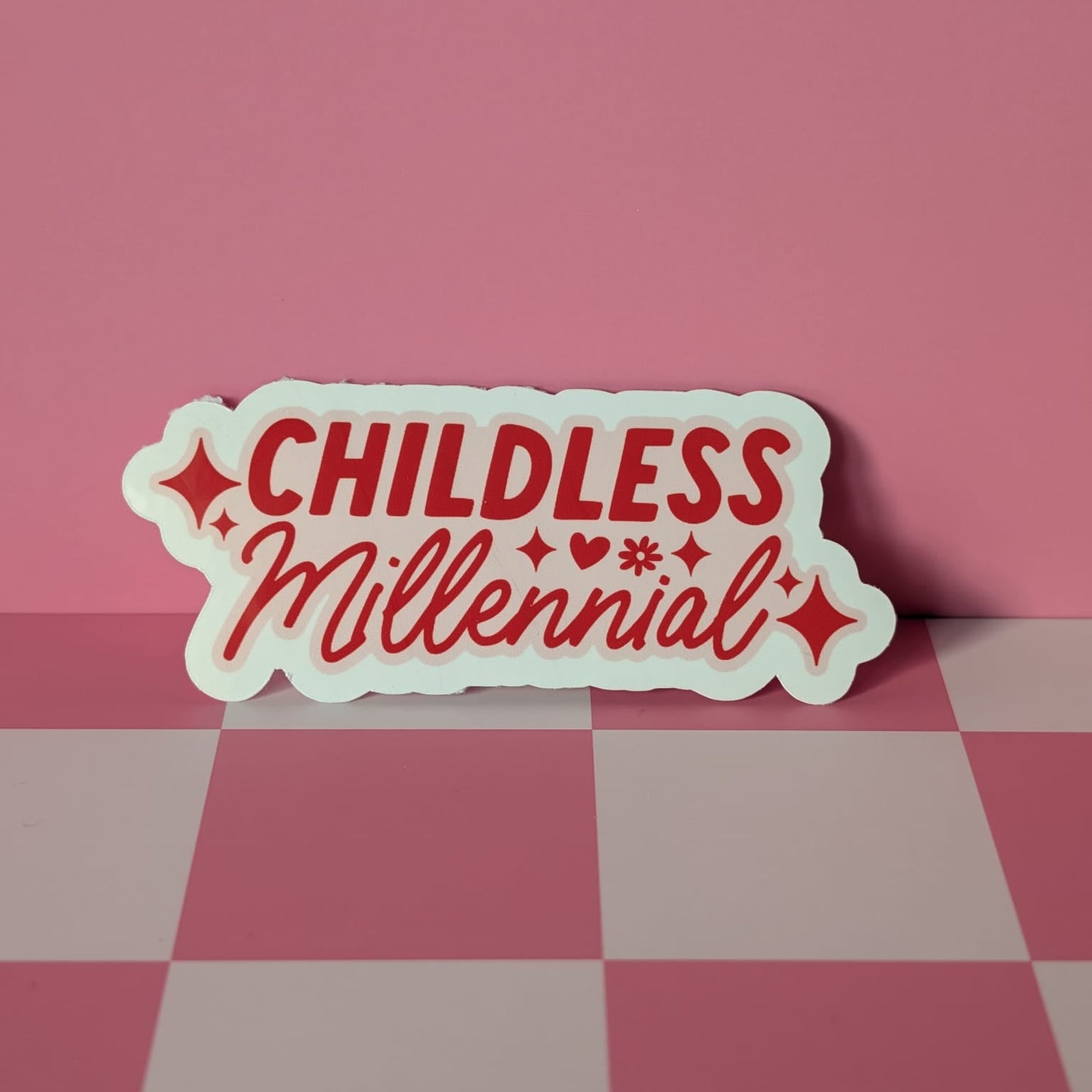 Sticker with 'CHILDLESS Millennial' text on a pink and gray checkered surface