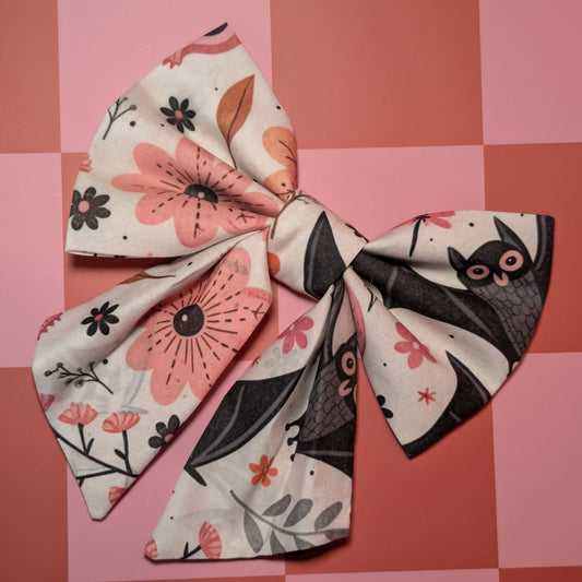 Large fabric bow with floral and cat pattern on a pink checkered background