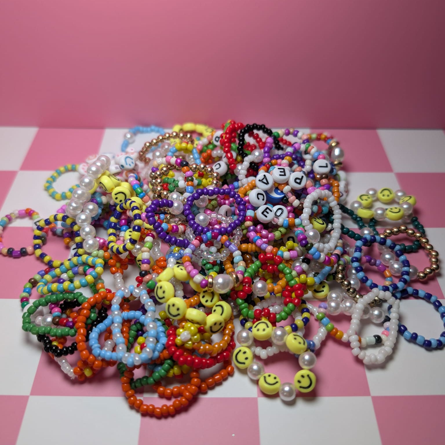 Colorful beaded bracelets on a pink and white checkered surface