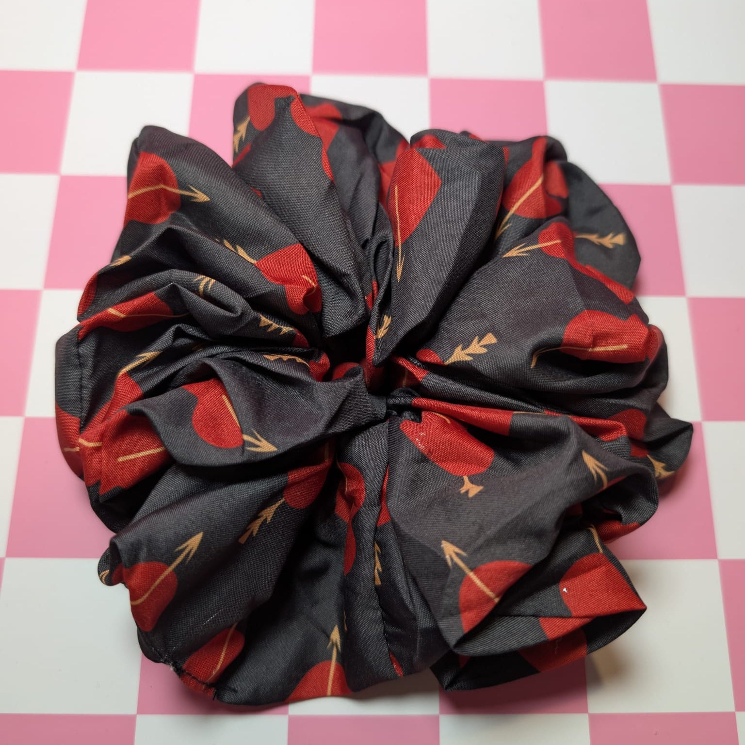 Black scrunchie with red floral pattern on a pink and white checkered background