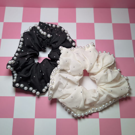 Black and white scrunchies with pearl embellishments on a pink checkered background