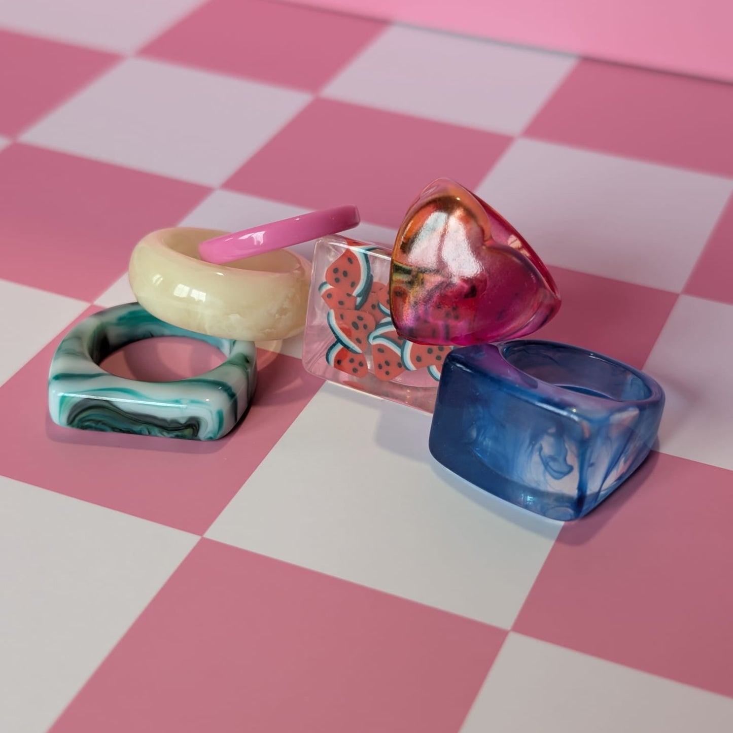 Colorful rings on a pink and white checkered surface