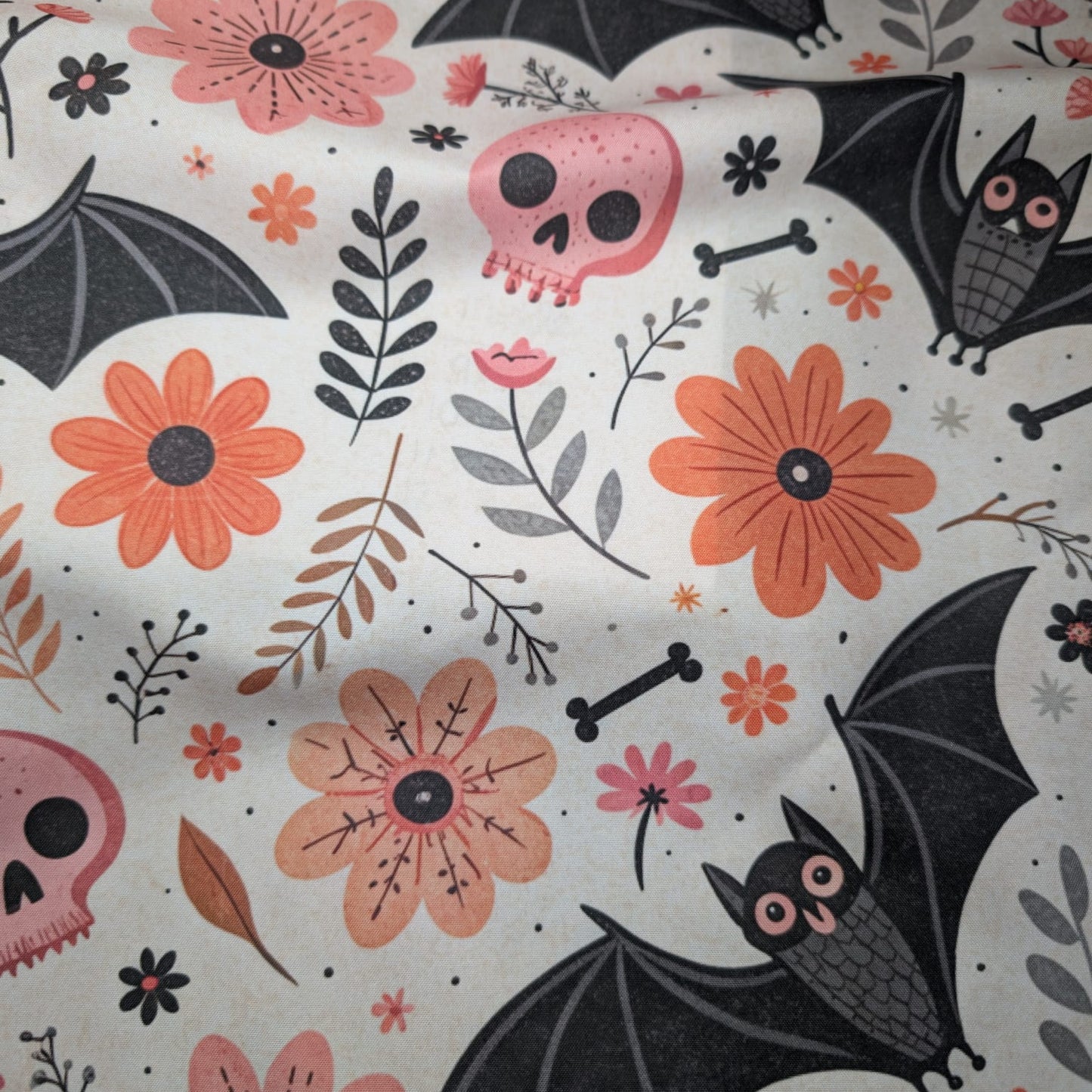 Halloween-themed fabric with bats, skulls, and flowers on a white background