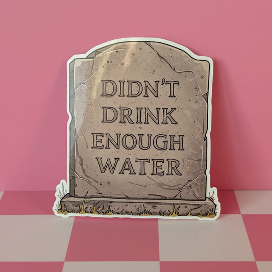 Graveyard tombstone sign with 'Didn't Drink Enough Water' text on a pink and white checkered background