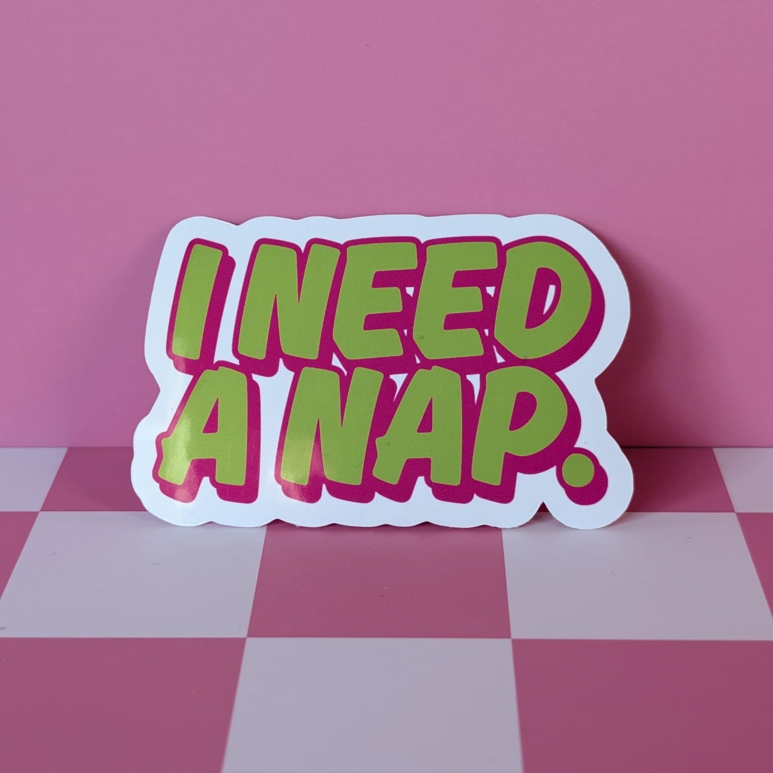 Sticker with 'I NEED A NAP.' text on a pink checkered floor