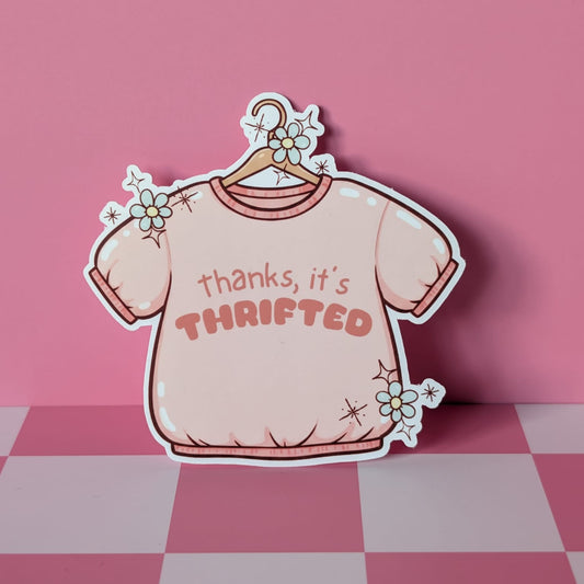 Sticker of a pink shirt on a hanger with 'thanks, it's thrifted' text on a pink checkered floor.