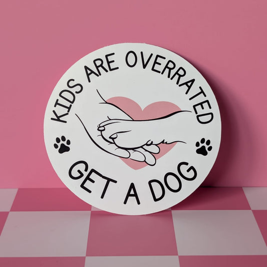 Circular sign with text 'Kids are overrated, get a dog' on a pink background