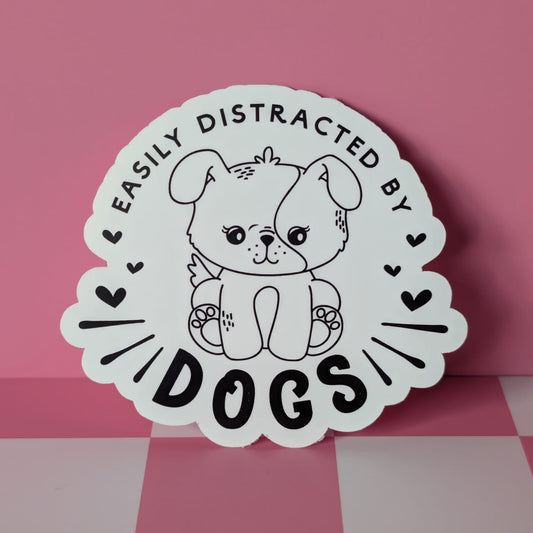 Sticker with a dog illustration and text 'Easily Distracted by Dogs' on a pink background
