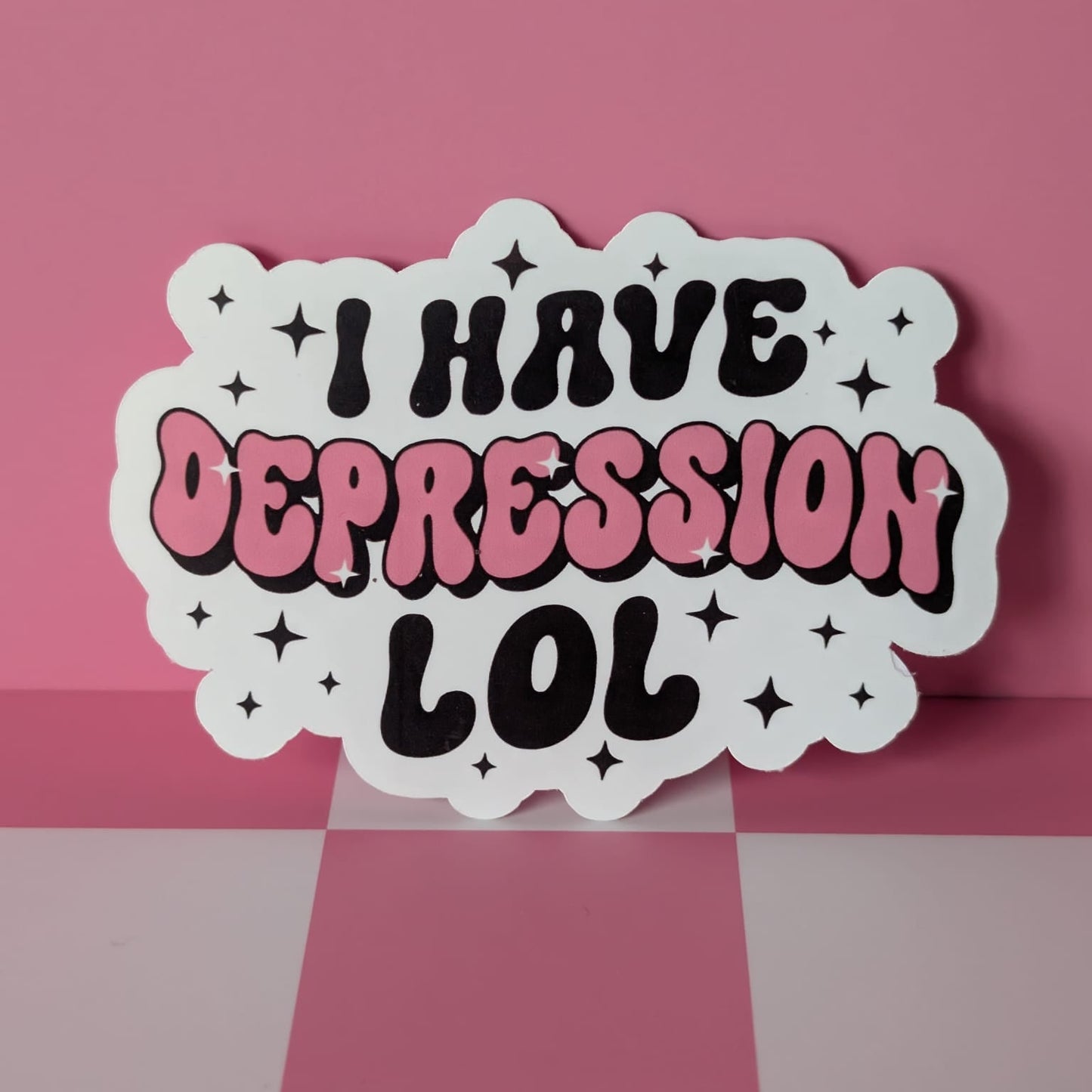 Sticker with 'I HAVE DEPRESSION LOL' text on a pink and gray checkered background